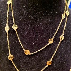 Extra long, gold tone chain with swirl designs.